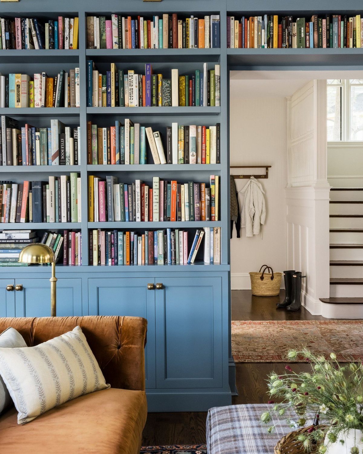 Blue built-in bookcases filled with books next to a brown leather sofa.