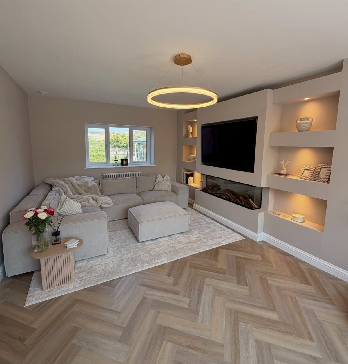 Light wood herringbone flooring in a modern living room with a grey sectional sofa.