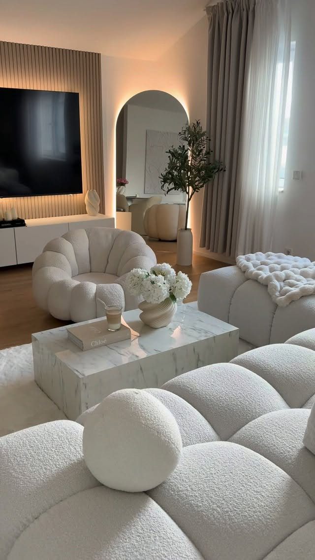 White bouclé rounded sofa and chair around a marble coffee table in modern room