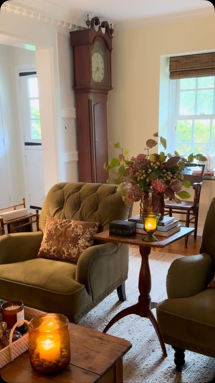 Olive green tufted armchairs and a tall antique grandfather clock in a cozy room.