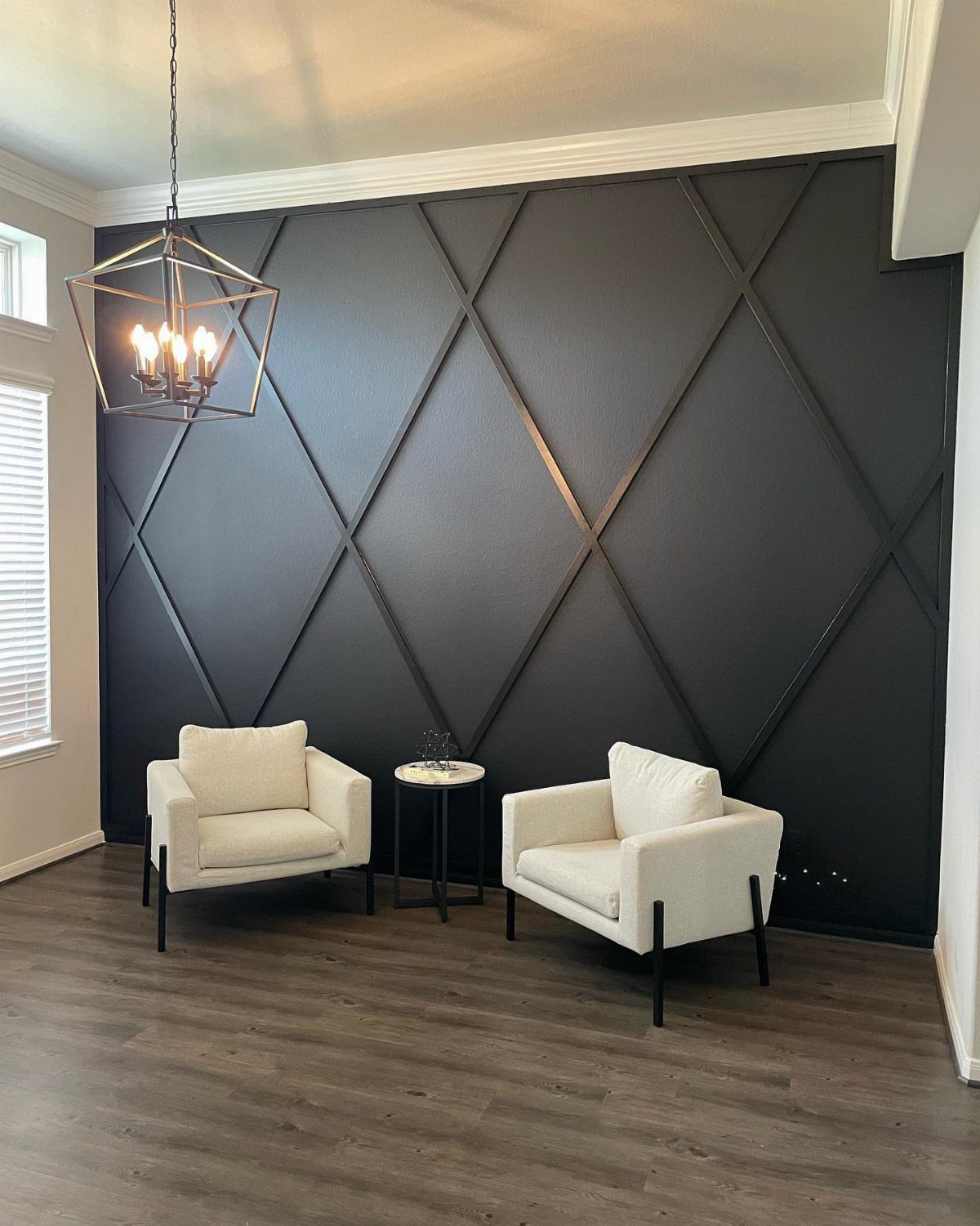 Black accent wall with diamond wood molding and two white armchairs