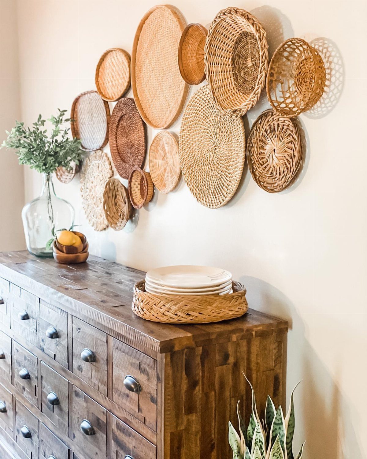 Woven wicker baskets of various sizes arranged as a decorative wall display above a dresser.