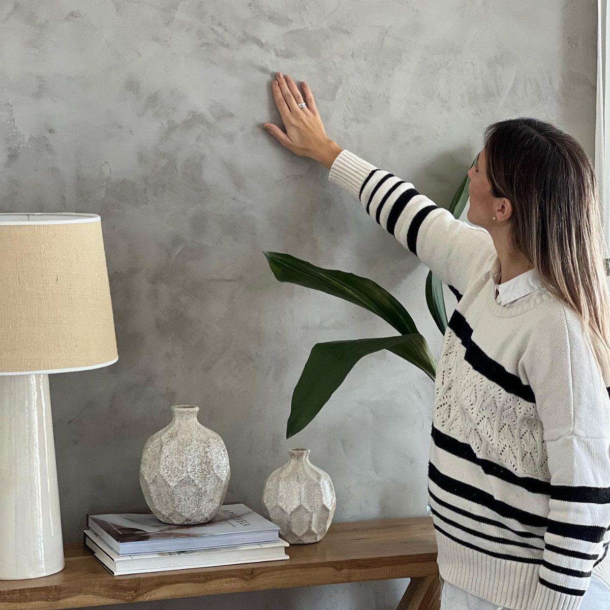 Woman touching a grey textured concrete accent wall in a modern living room