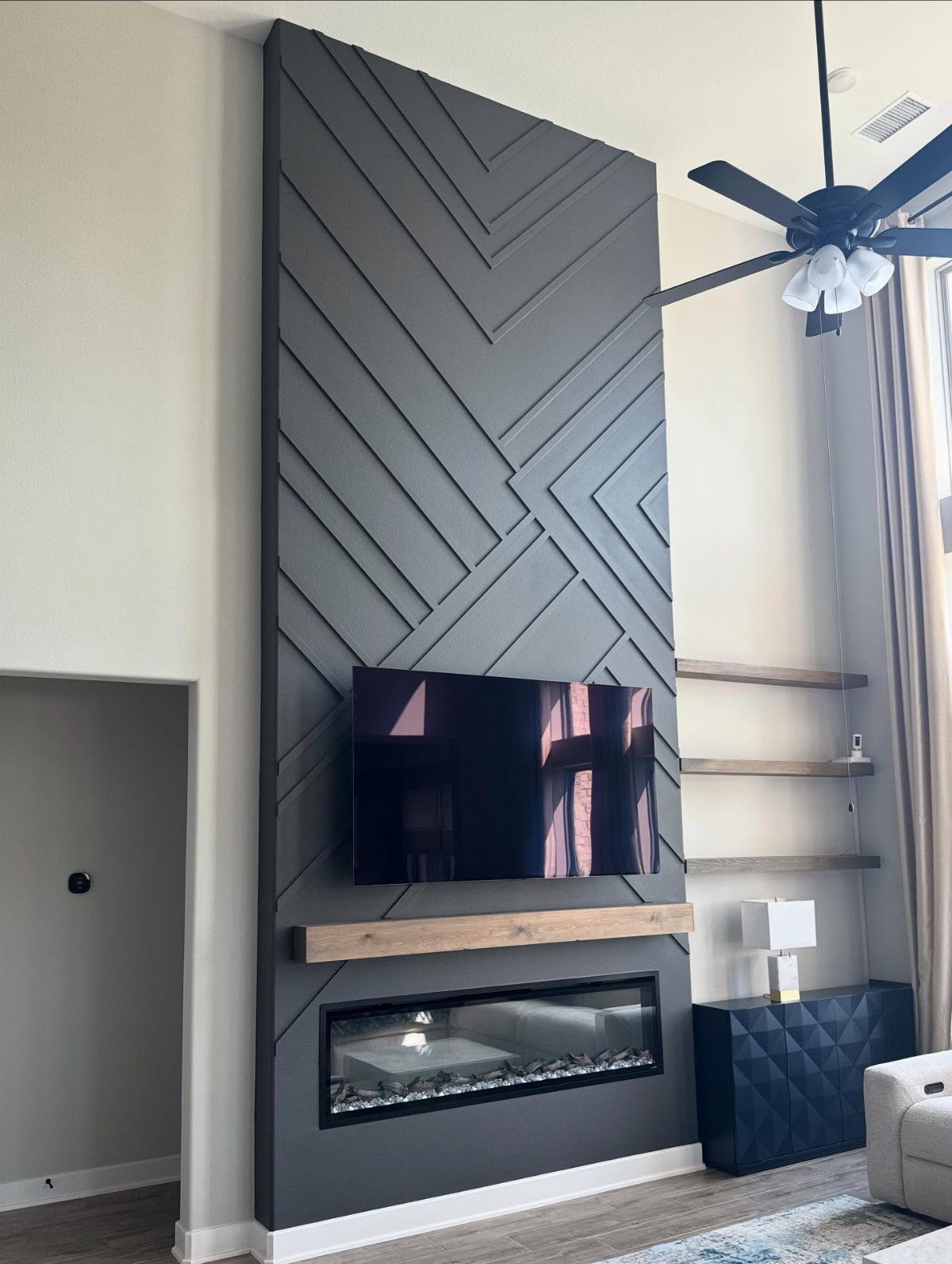 Dark grey geometric accent wall with a mounted TV and linear fireplace