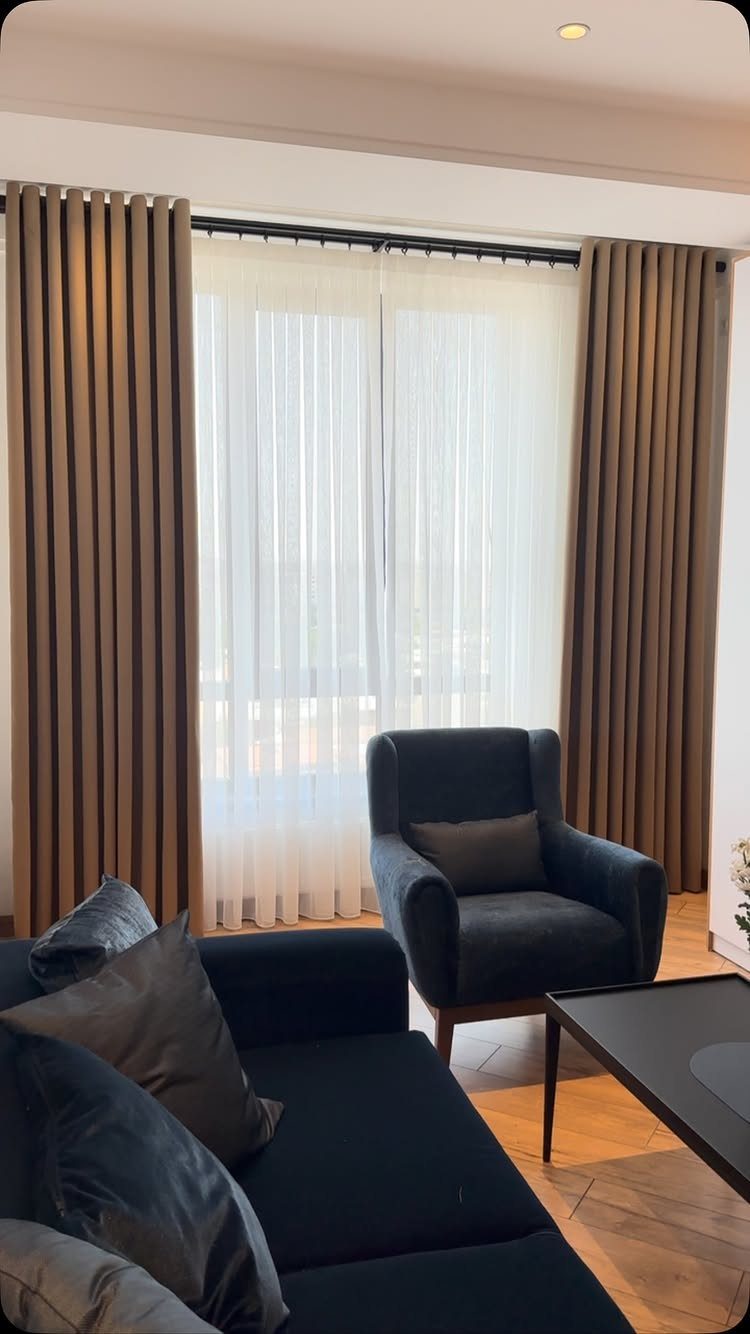 Brown and white curtains hung high above a window in a modern living room.
