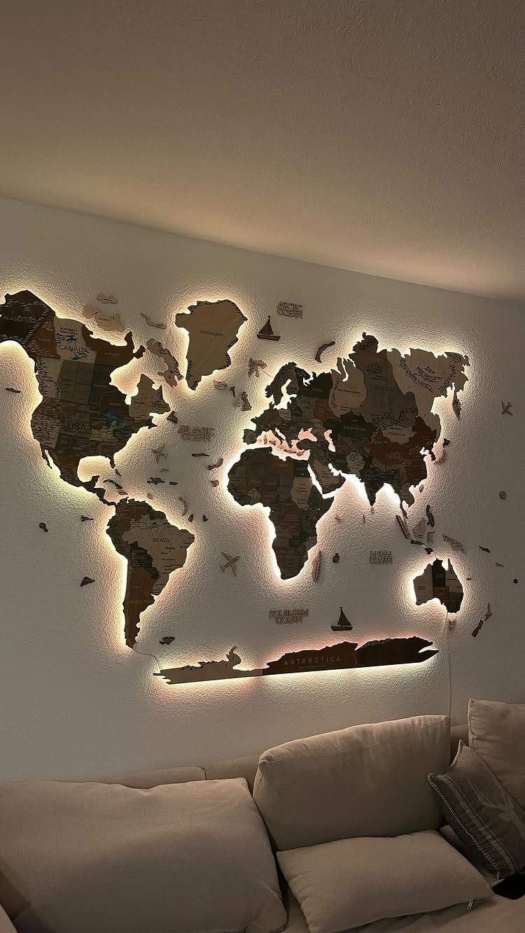 Backlit wooden world map mounted on a wall above a neutral colored couch