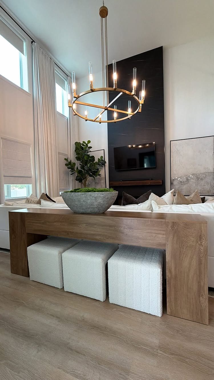 Wooden console table behind a white sofa with three white ottomans underneath.
