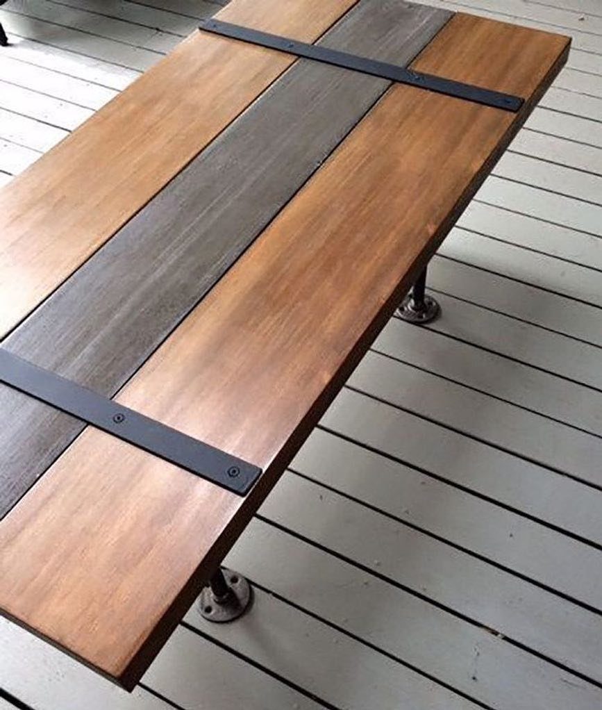 Wooden table with industrial metal pipe legs on a grey wooden deck
