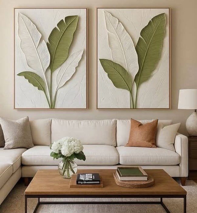 White sectional sofa with two large tropical leaf art pieces on the wall behind