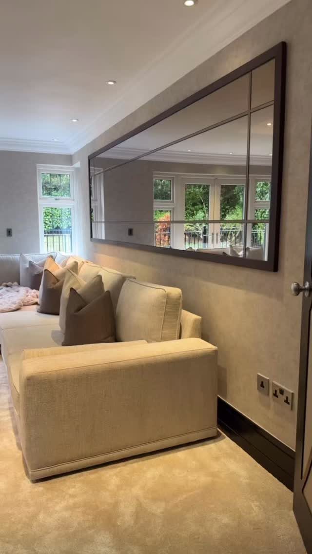 Beige sectional sofa with a large framed grid mirror on the wall behind it.