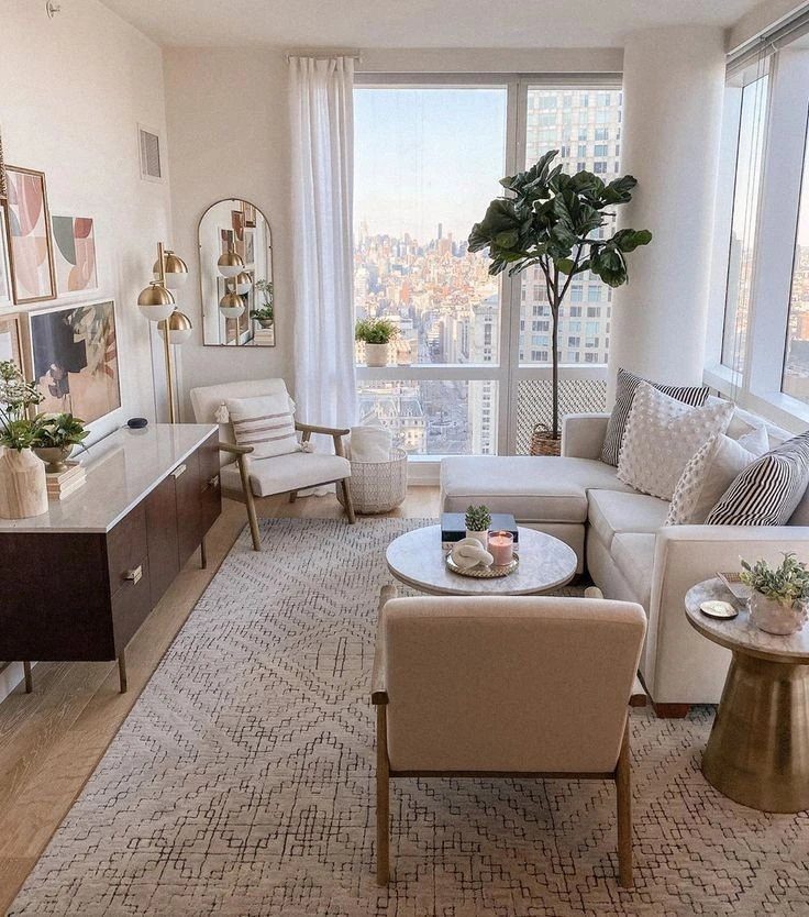 Beige sectional couch and armchairs in a bright city apartment living room