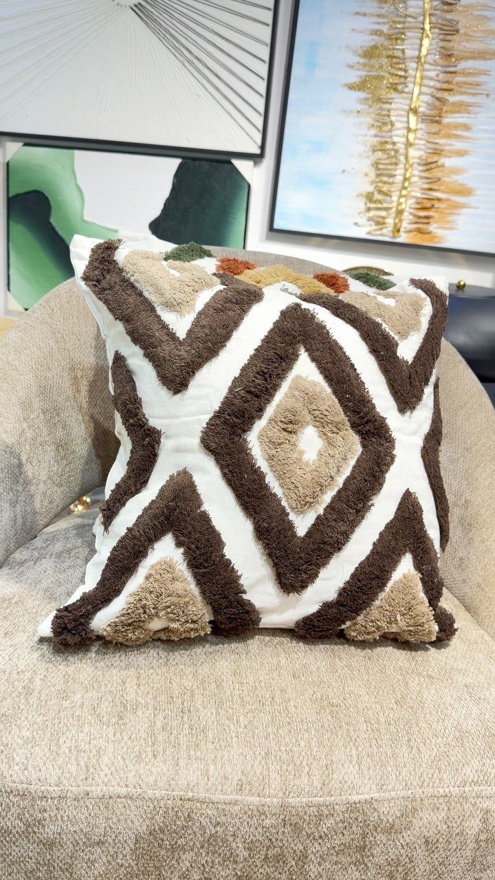 Textured white and brown geometric throw pillow on a beige fabric couch.