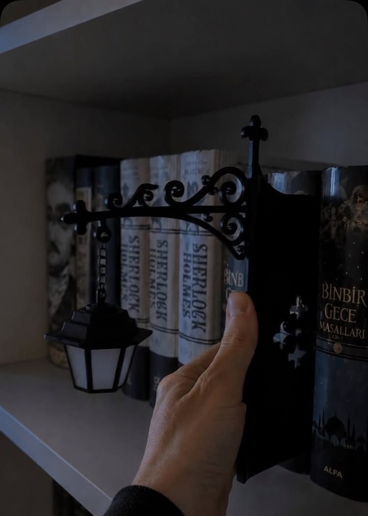 Black street lamp bookend holding Sherlock Holmes books on a white shelf.