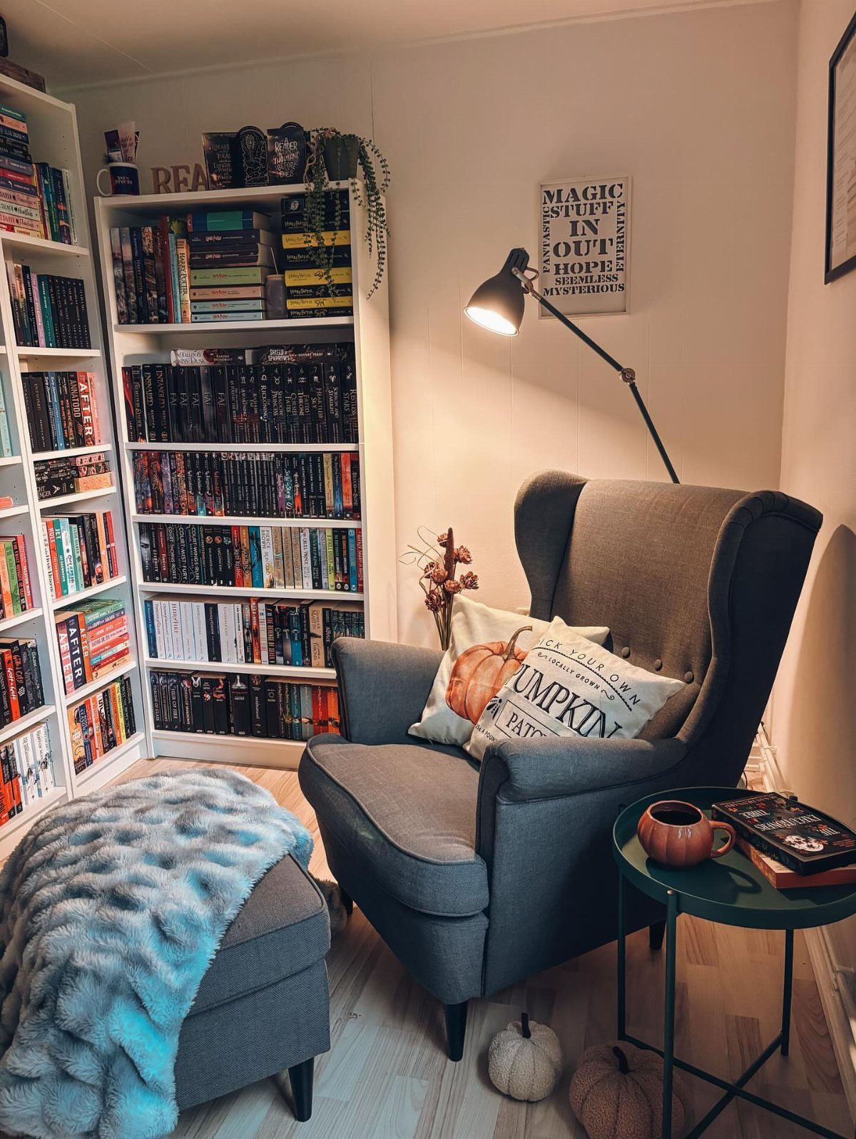 Grey wingback armchair and ottoman next to white bookshelves in a cozy reading nook.
