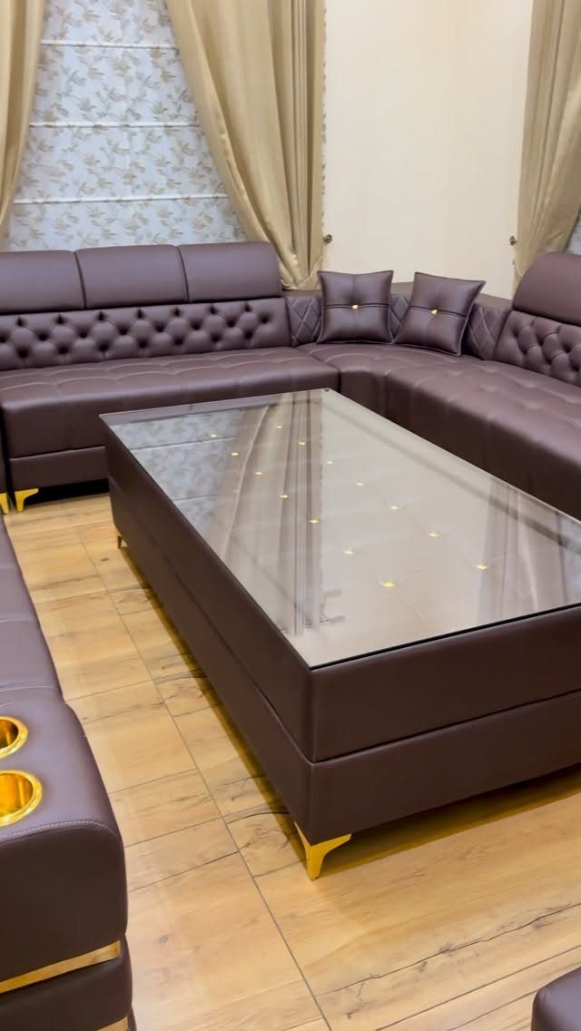 Dark brown leather sectional sofa and matching glass-top coffee table in a living room.