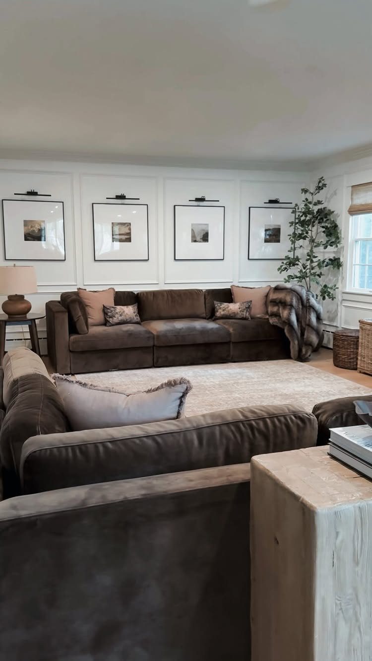 Brown fabric sofas in a living room with framed art on white walls.