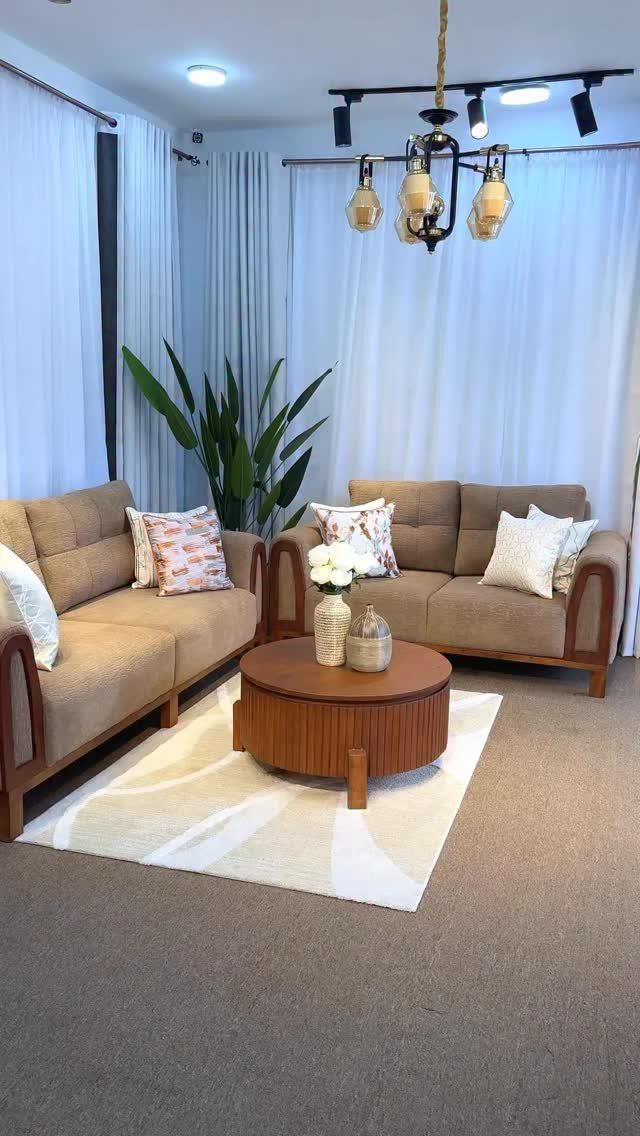 Brown fabric sofas and a round wooden coffee table on a white rug.