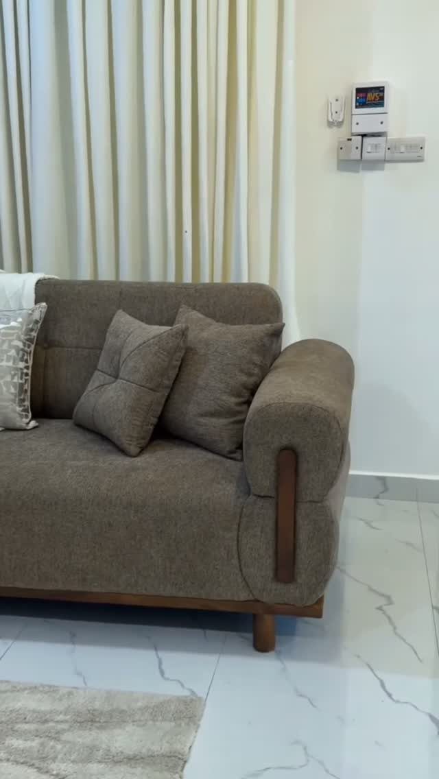 Brown fabric sofa with pillows in a living room with white marble flooring.