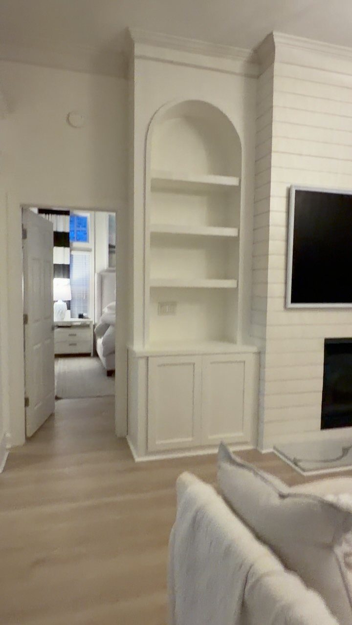 White built-in shelving and cabinets next to a fireplace and mounted television.