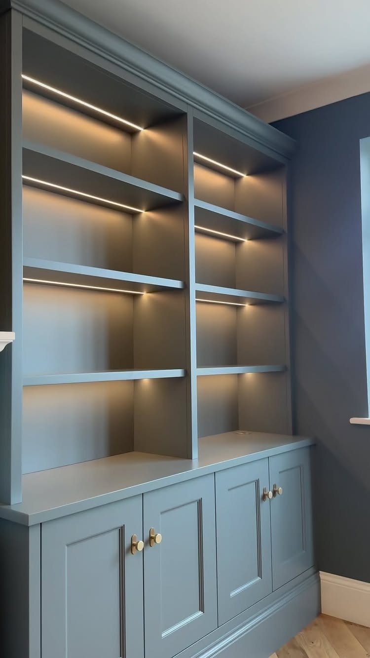Blue-grey built-in alcove shelving with integrated lighting and lower storage cabinets.