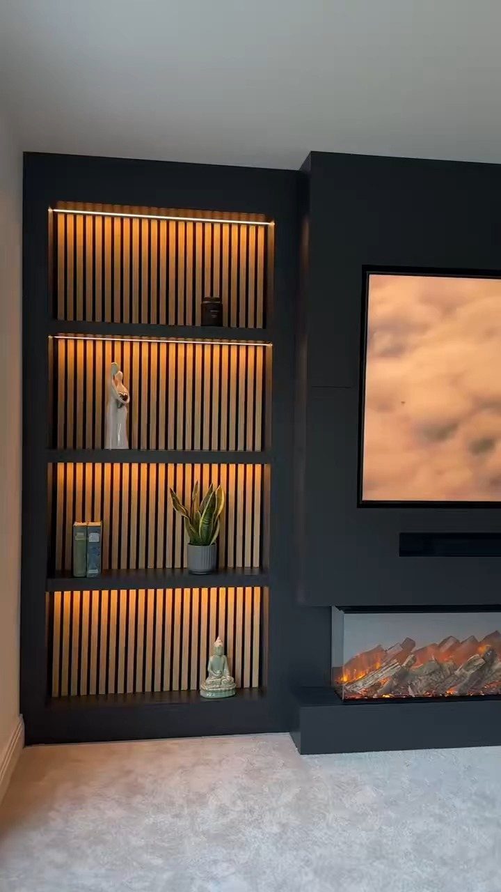 Dark grey built-in shelves with LED lighting next to a modern fireplace and TV.