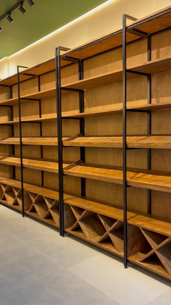 Wooden built-in shelves with black metal supports and wine racks at the base.