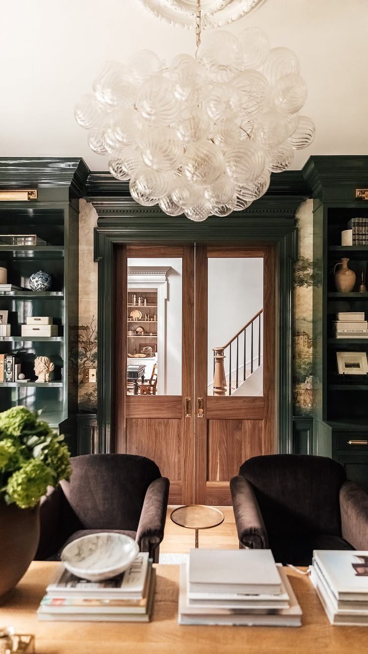 Dark green built-in bookshelves flanking wooden double doors in a luxury living room.