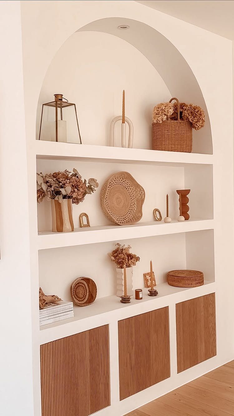 White arched built-in shelving unit with decorative vases and fluted wooden cabinets.