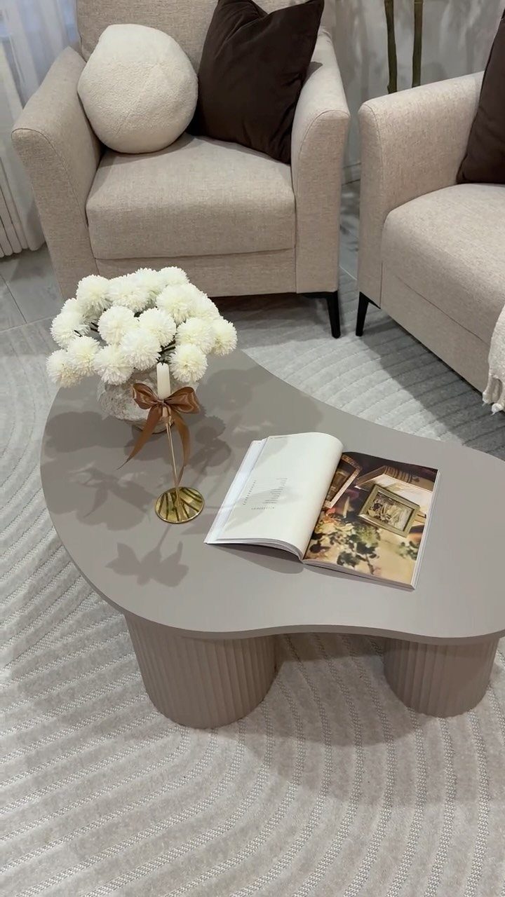 Grey organic coffee table with white flowers and two beige armchairs on a rug