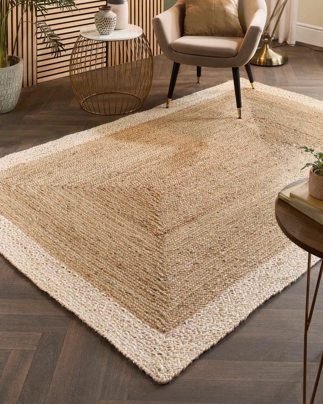 Woven jute rug with a light border on a dark herringbone wood floor.