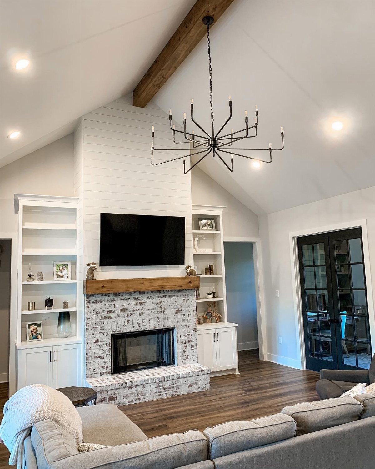 Living room with a black chandelier, recessed lighting, and a stone fireplace.