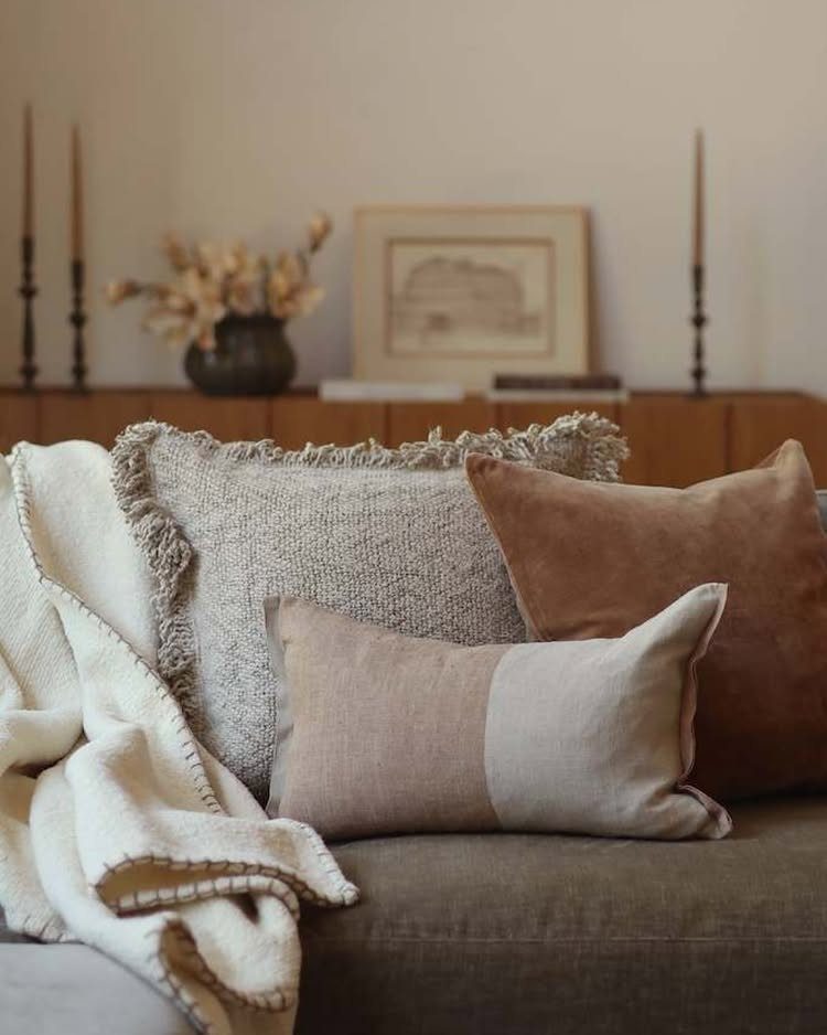Textured pillows and a white throw blanket on a grey contemporary farmhouse sofa.