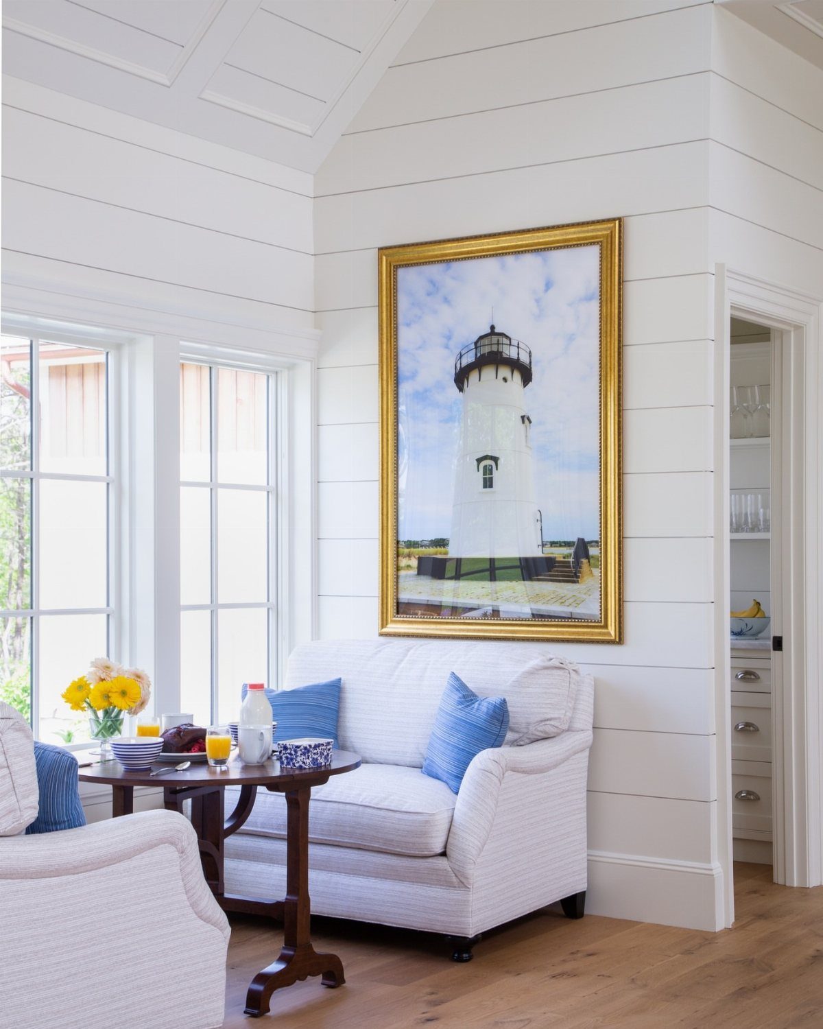 White shiplap walls in a bright living room with a white slipcovered sofa.
