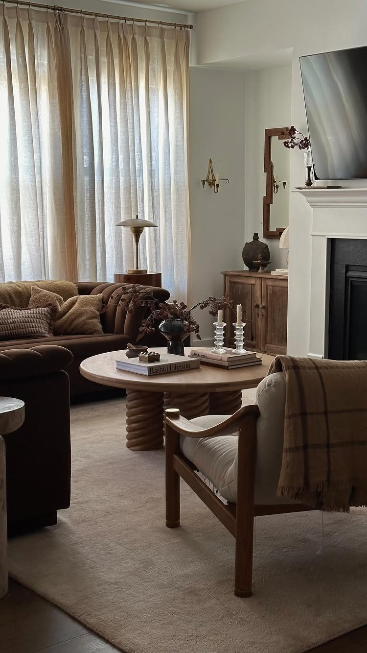 Plush brown sectional and wooden armchair in a cozy, neutral-toned contemporary living room.