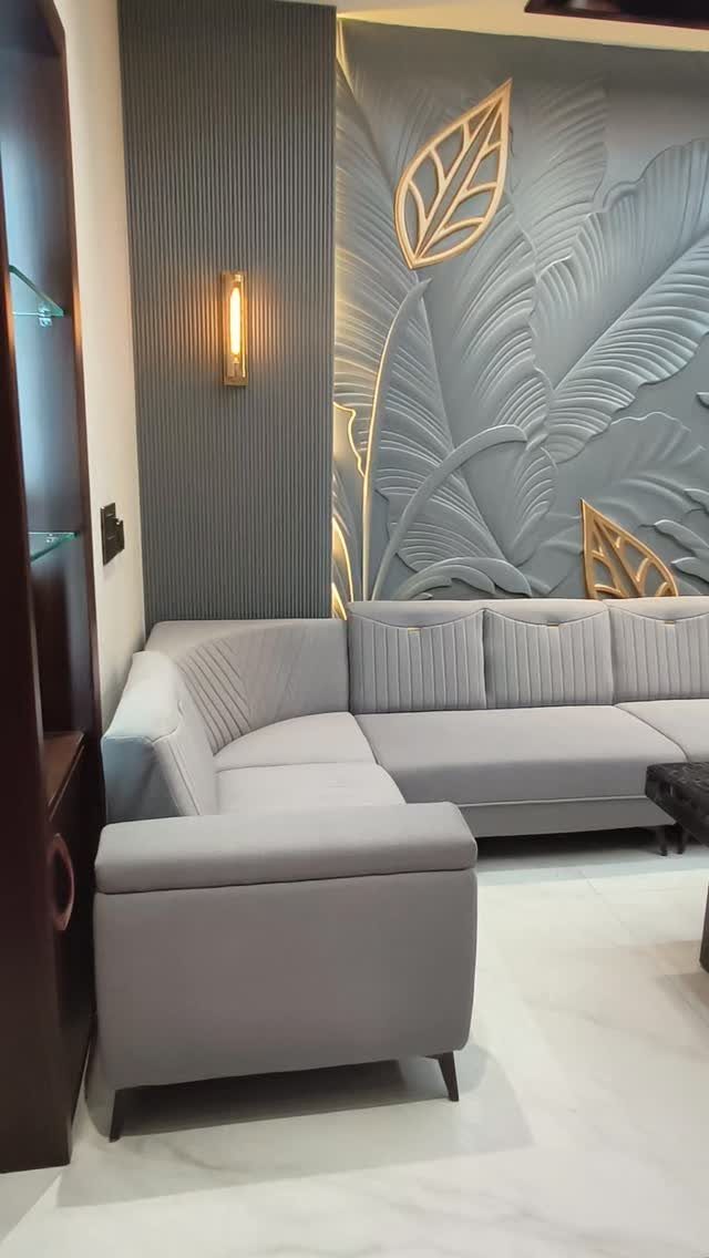 Grey sectional sofa in front of a 3D sculpted wall with gold accents.
