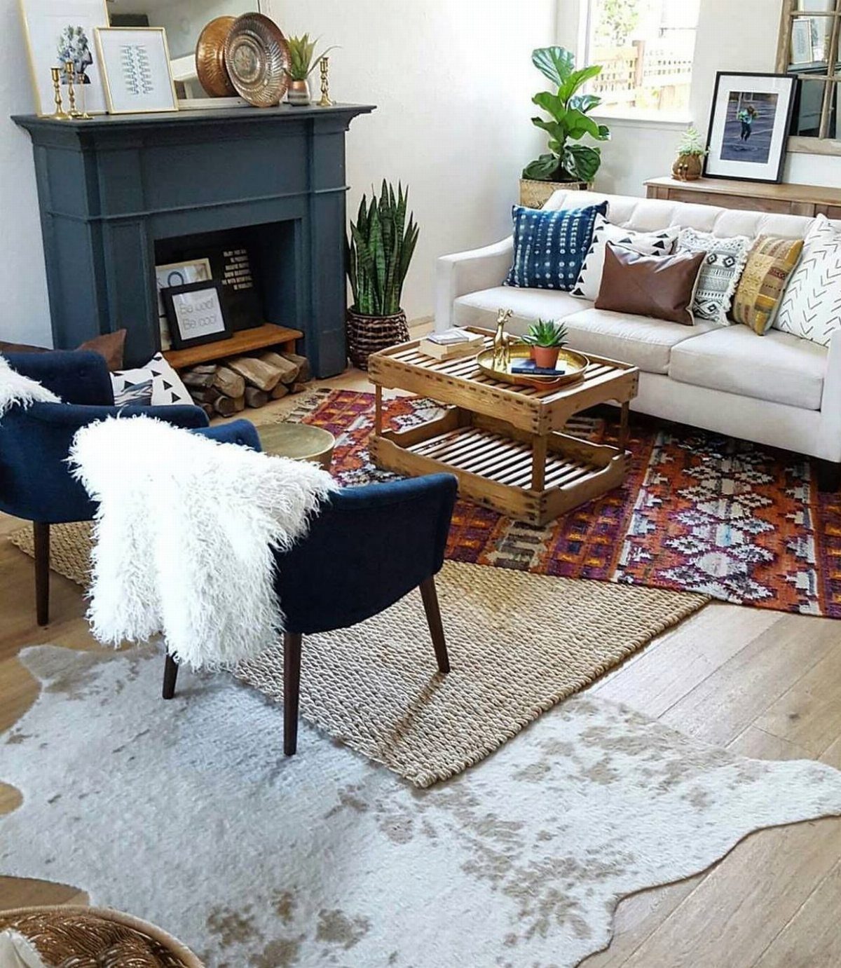 Layered rugs in a living room with a white sofa and blue chairs.