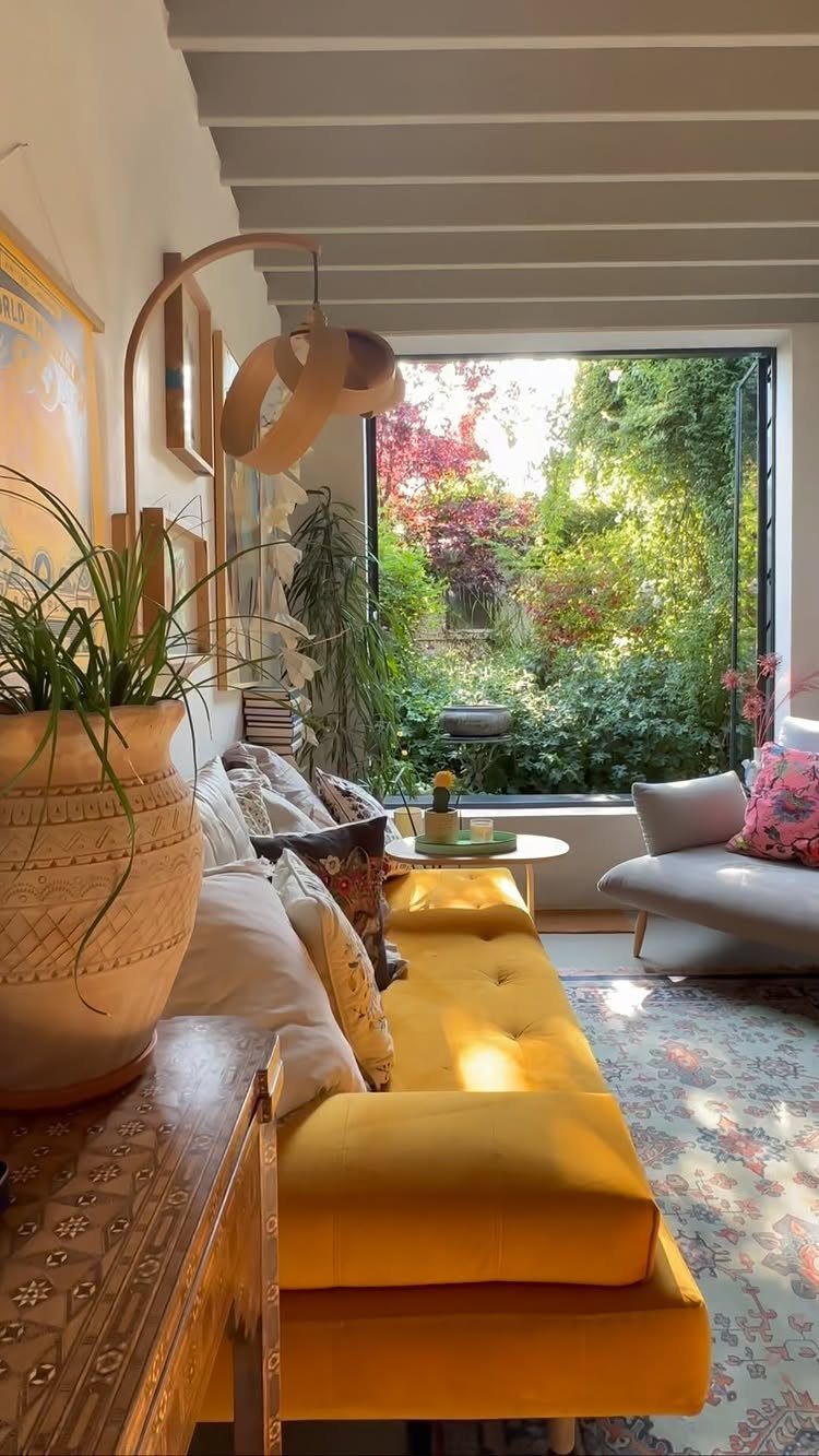 Bright living room with yellow velvet sofa and large window overlooking a garden