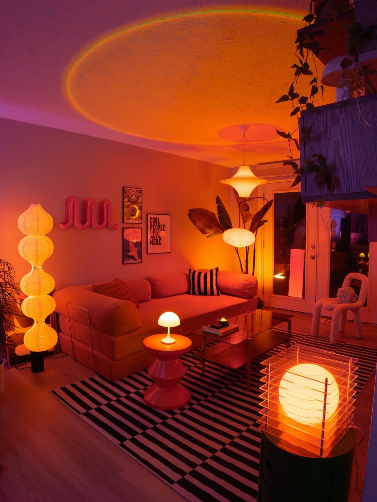 Modern living room with pink sofa and multiple glowing warm orange lamps.