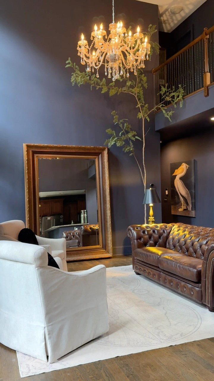 Brown leather sofa and white armchair facing each other on a white rug.