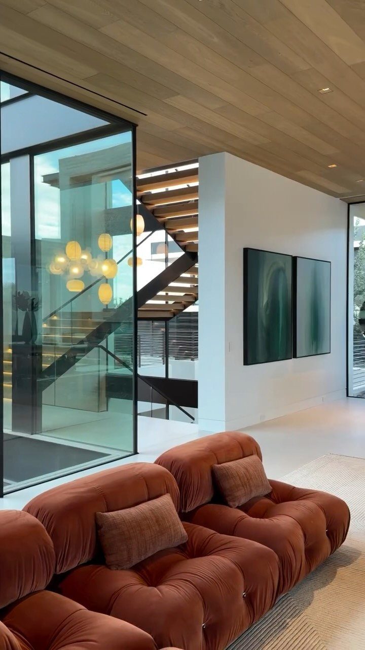 Rust-colored modular sofa in a modern living room with large glass walls.