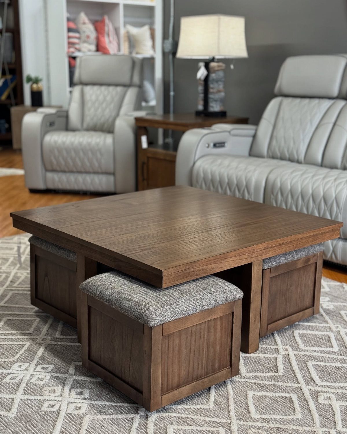 Wooden coffee table with nested grey ottomans in a living room setting