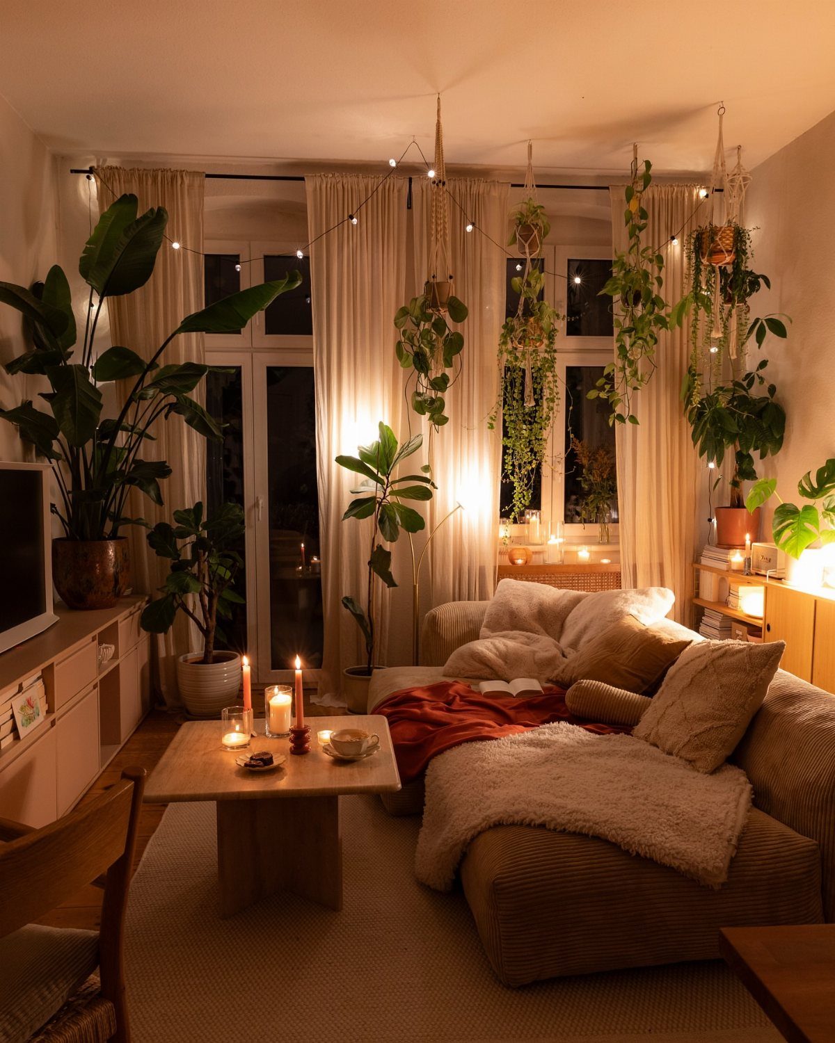 Cozy living room with lit candles on a wooden table and plush sofa.