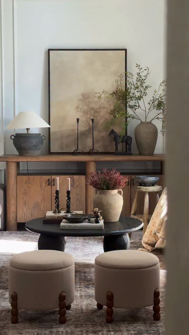 Living room with wooden furniture, black coffee table, and beige upholstered ottomans.
