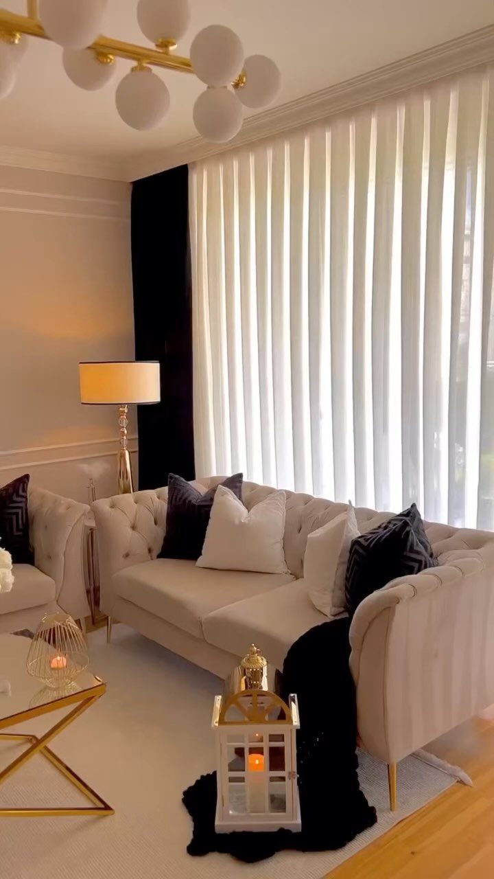Tufted cream sofa with gold accents and black cushions in a bright living room.