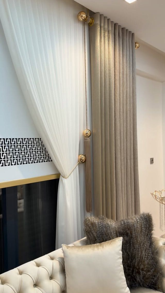 Beige and white curtains with gold hardware above a white tufted sofa.