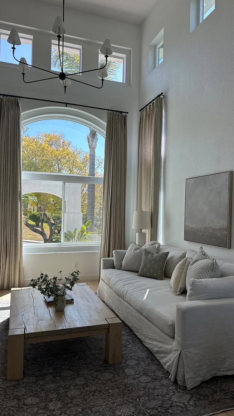 Beige curtains framing an arched window in a neutral toned modern living room