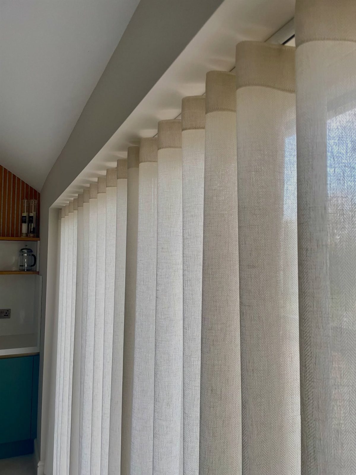 Off-white textured S-fold curtains hanging from a recessed ceiling track in a room.