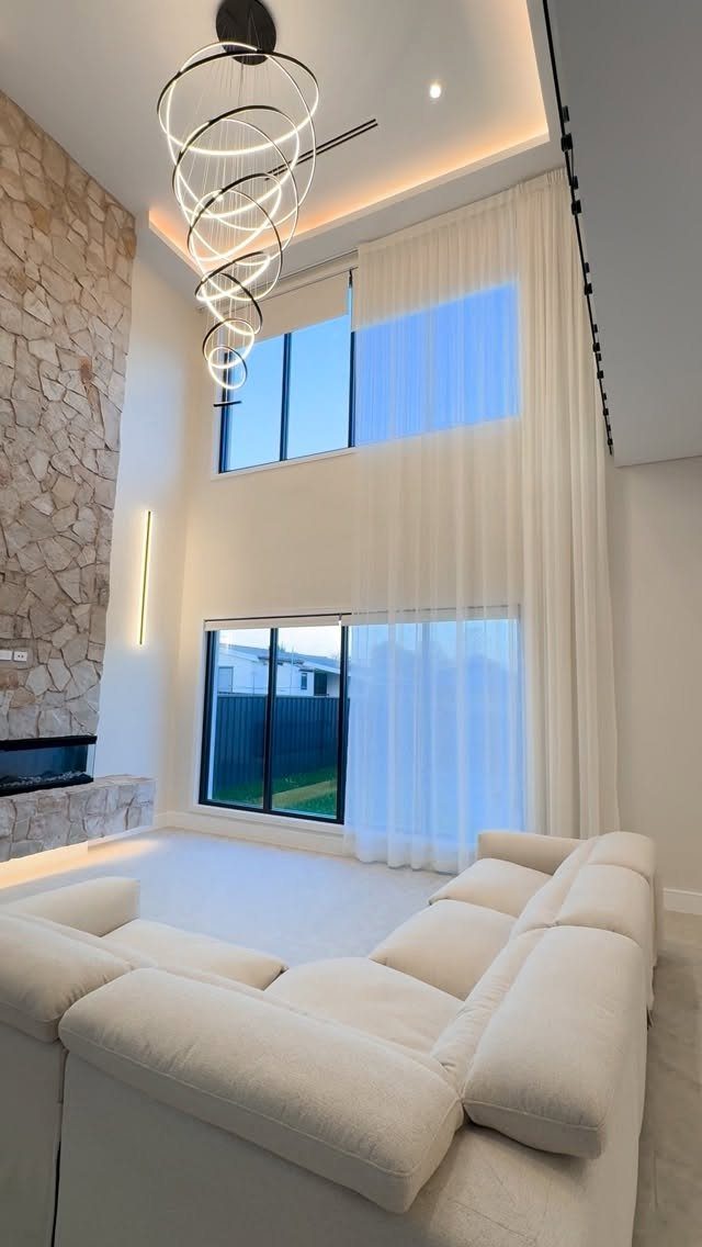 White sheer curtains in a modern living room with a white sectional sofa.