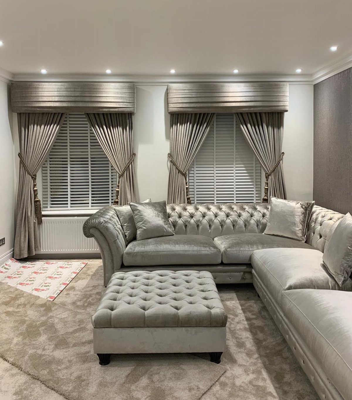 Grey tufted sofa in a living room with curtains and traditional fabric pelmets.