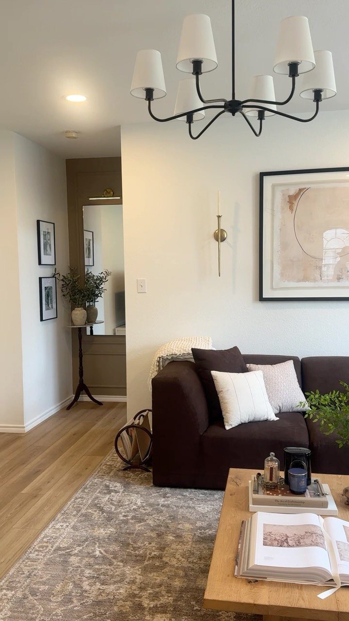 Modern living room with dark brown sofa, white pillows, and framed wall art.